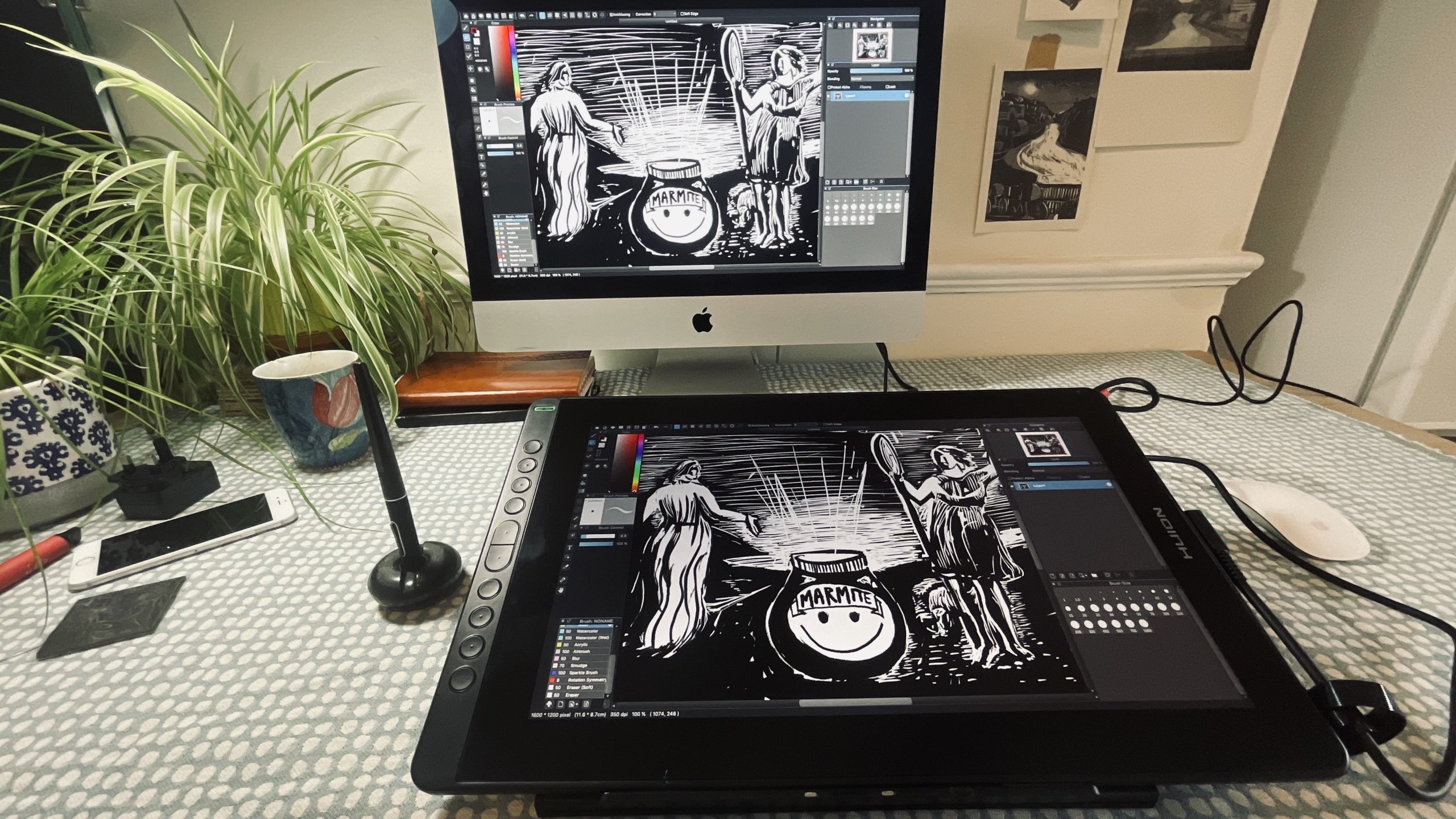 A shot of the Huion Kamvas 16 on a desk in front of a monitor.