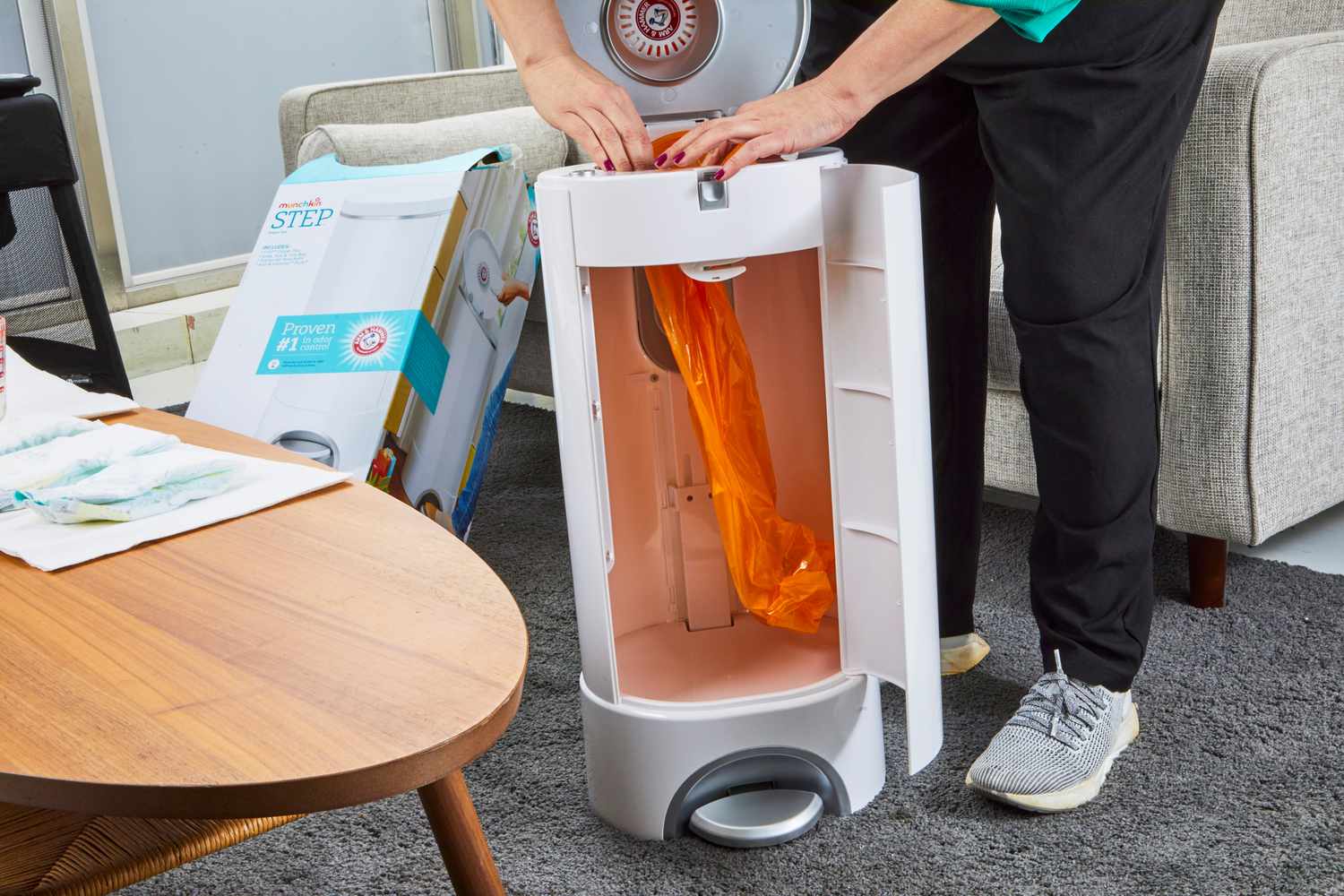 An orange bag is placed inside of the Arm & Hammer Munchkin Step Diaper Pail Powered