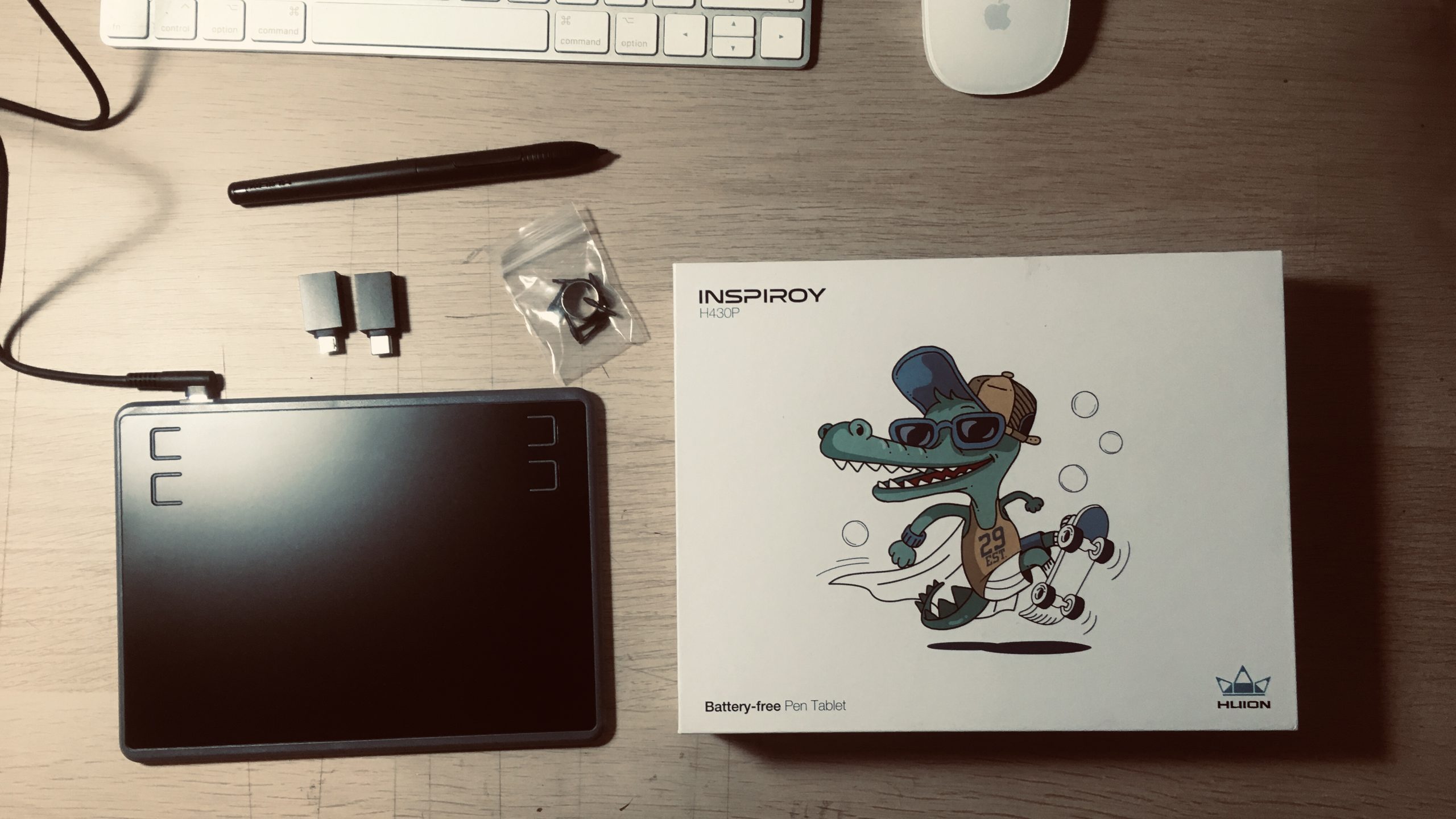 The Huion H430P pen tablet and accessories on a faux wood desk.